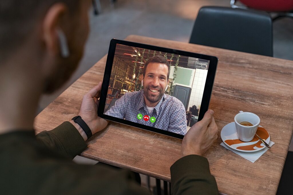 Man smiling on video call in cafe