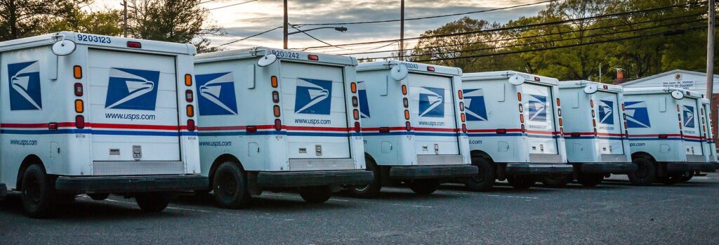 USPS mail trucks parked in a lot